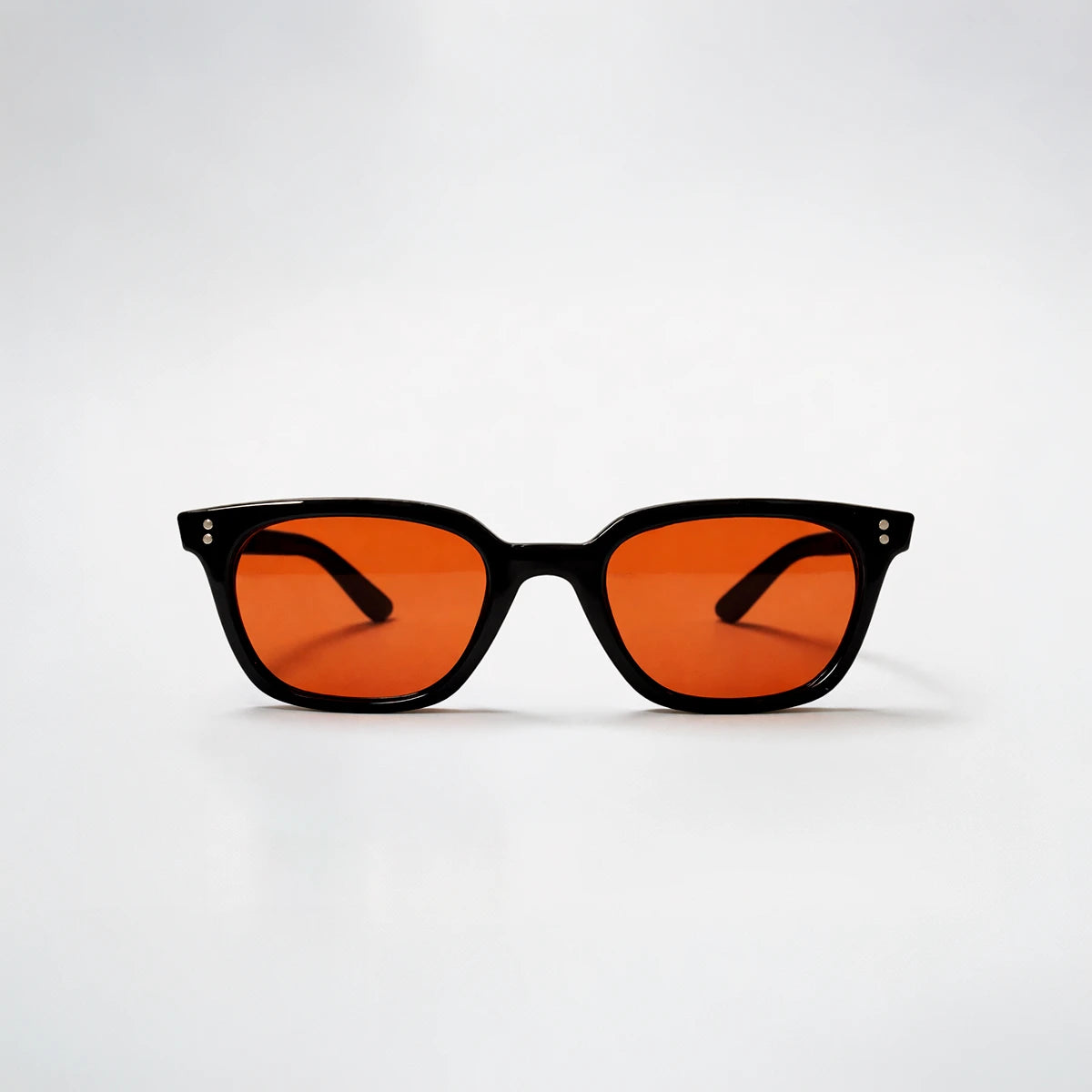 Gafas de sol rectangulares Capri Sunset con montura gruesa negra y lentes en tono naranja brillante.
