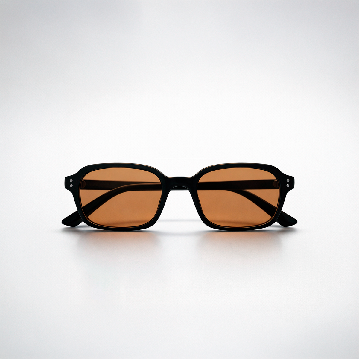 Gafas de sol rectangulares Lisbon Honey con montura gruesa negra y lentes en tono ámbar miel.
