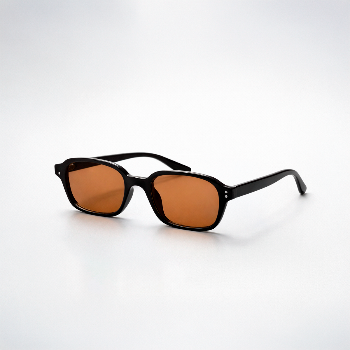 Gafas de sol rectangulares Lisbon Honey con montura gruesa negra y lentes en tono ámbar miel.
