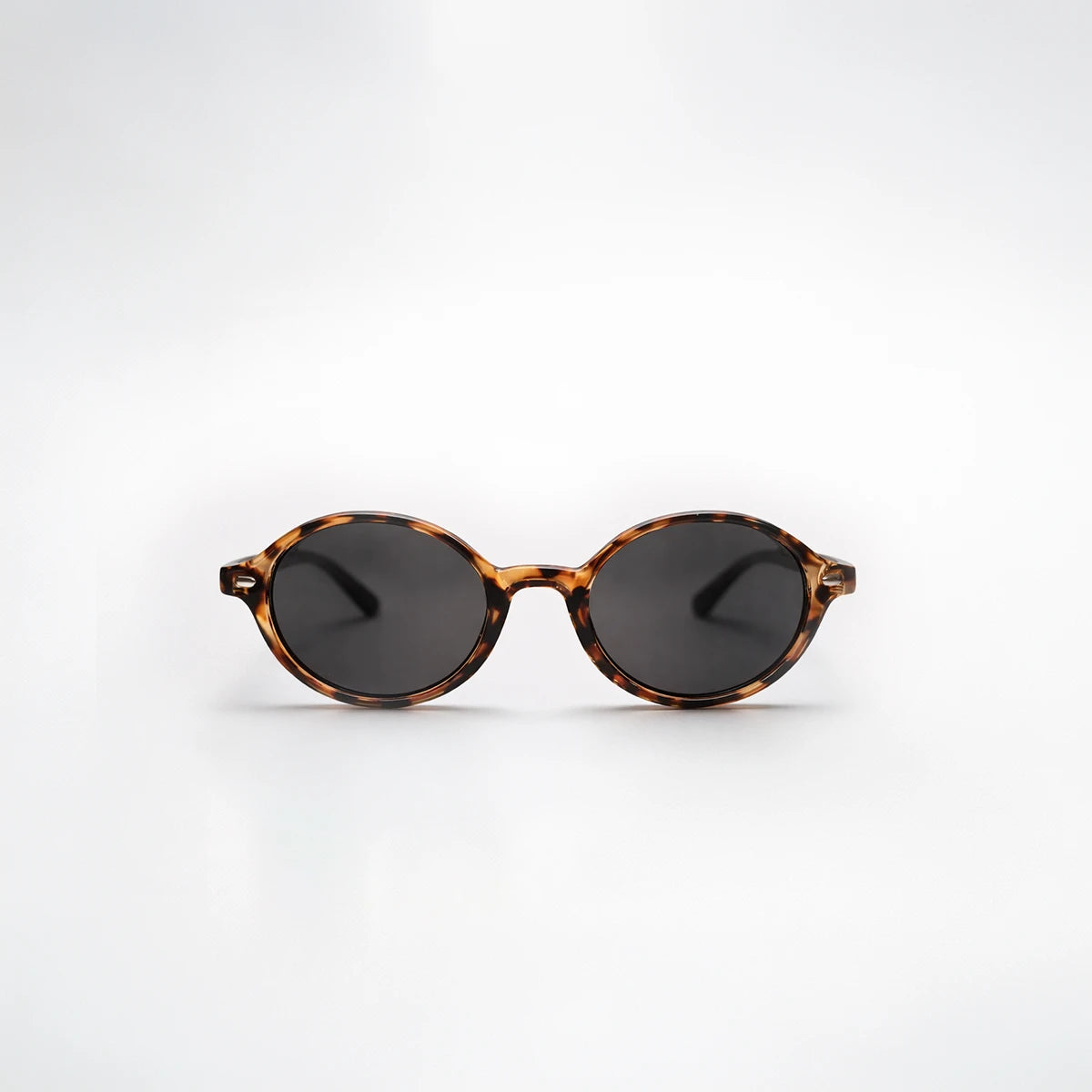 Gafas de sol redondeadas London Carey con montura de carey ámbar, patillas negras y lentes gris ahumado.
