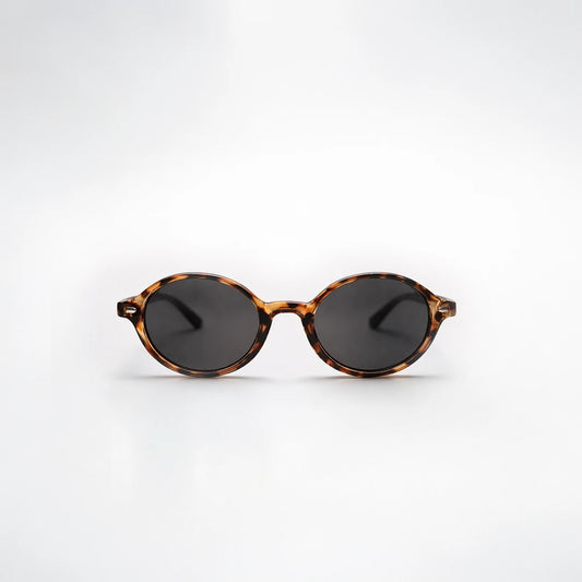 Gafas de sol redondeadas London Carey con montura de carey ámbar, patillas negras y lentes gris ahumado.
