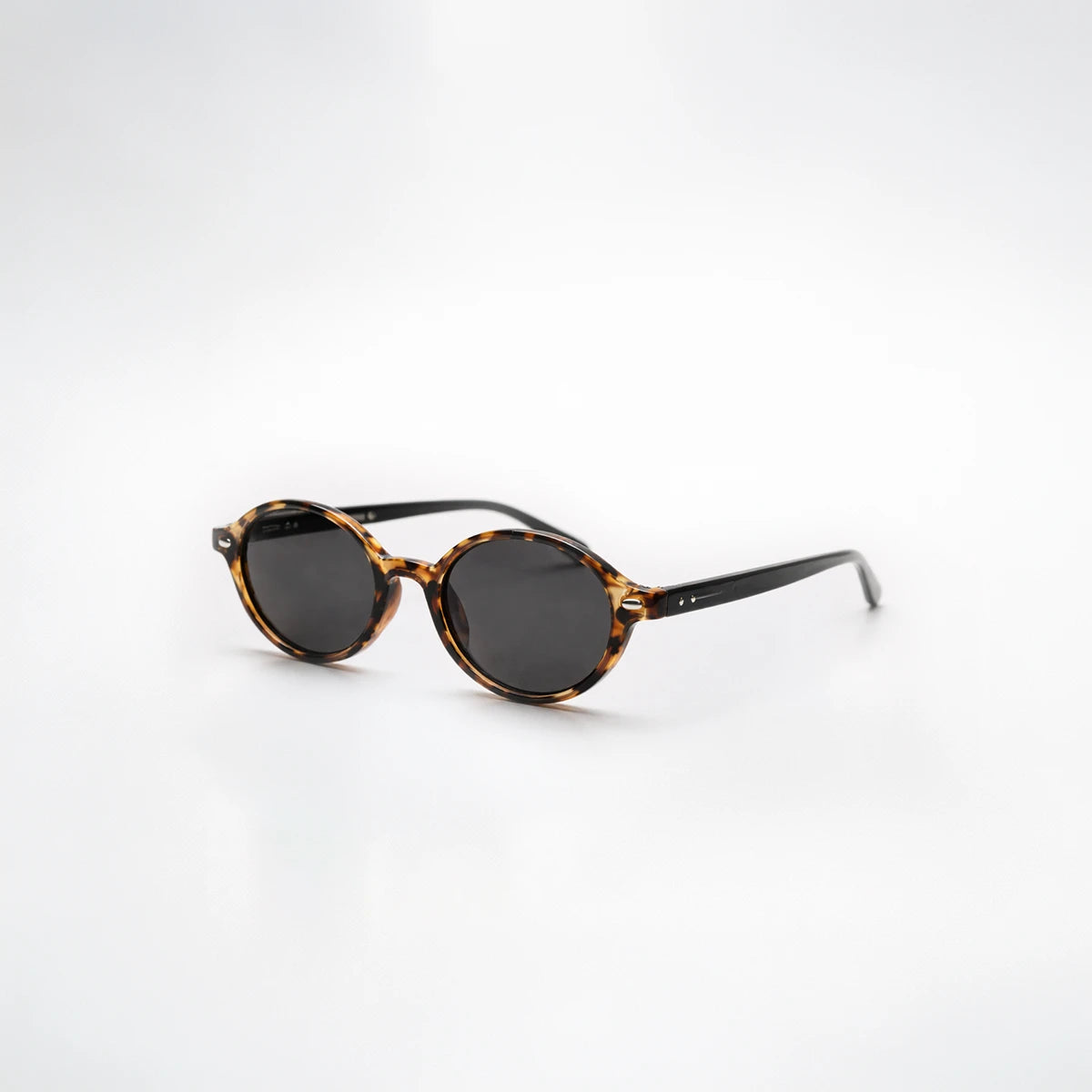 Gafas de sol redondeadas London Carey con montura de carey ámbar, patillas negras y lentes gris ahumado.
