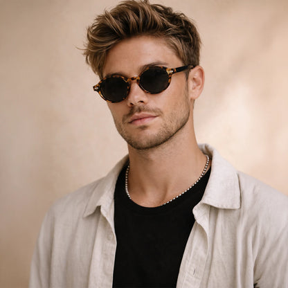 Gafas de sol redondeadas London Carey con montura de carey ámbar, patillas negras y lentes gris ahumado.
