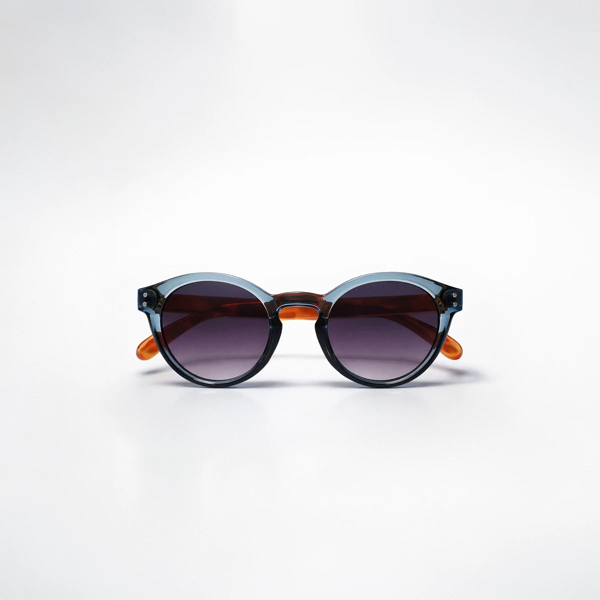 Gafas de sol redondeadas Paris Fade con montura azul translúcida, patillas de carey ámbar y lentes en degradado violeta.
