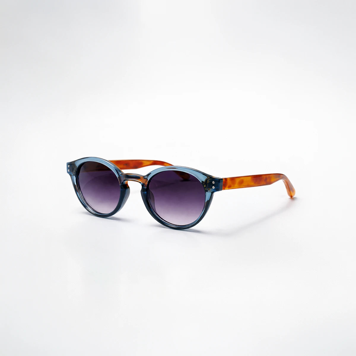 Gafas de sol redondeadas Paris Fade con montura azul translúcida, patillas de carey ámbar y lentes en degradado violeta.
