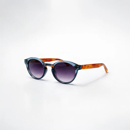 Gafas de sol redondeadas Paris Fade con montura azul translúcida, patillas de carey ámbar y lentes en degradado violeta.
