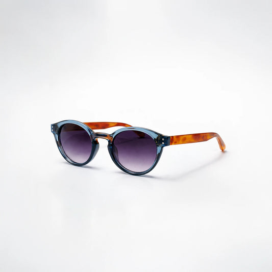 Gafas de sol redondeadas Paris Fade con montura azul translúcida, patillas de carey ámbar y lentes en degradado violeta.
