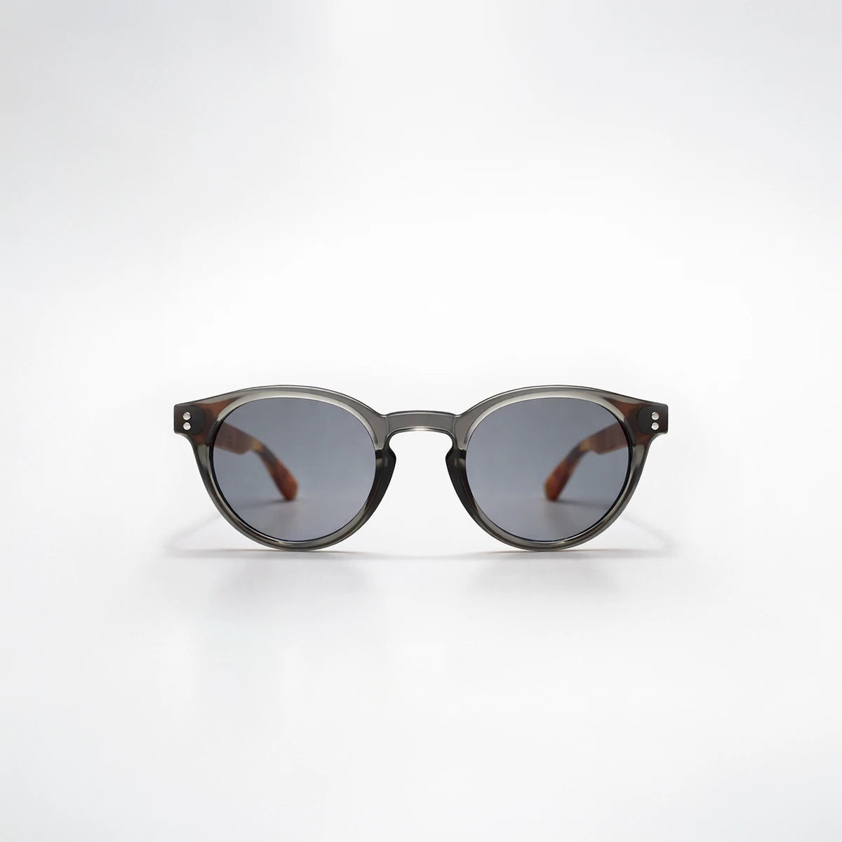 Gafas de sol redondeadas Paris Noir con montura negro translúcido, patillas de carey ámbar y lentes gris oscuro.
