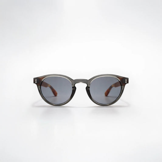 Gafas de sol redondeadas Paris Noir con montura negro translúcido, patillas de carey ámbar y lentes gris oscuro.
