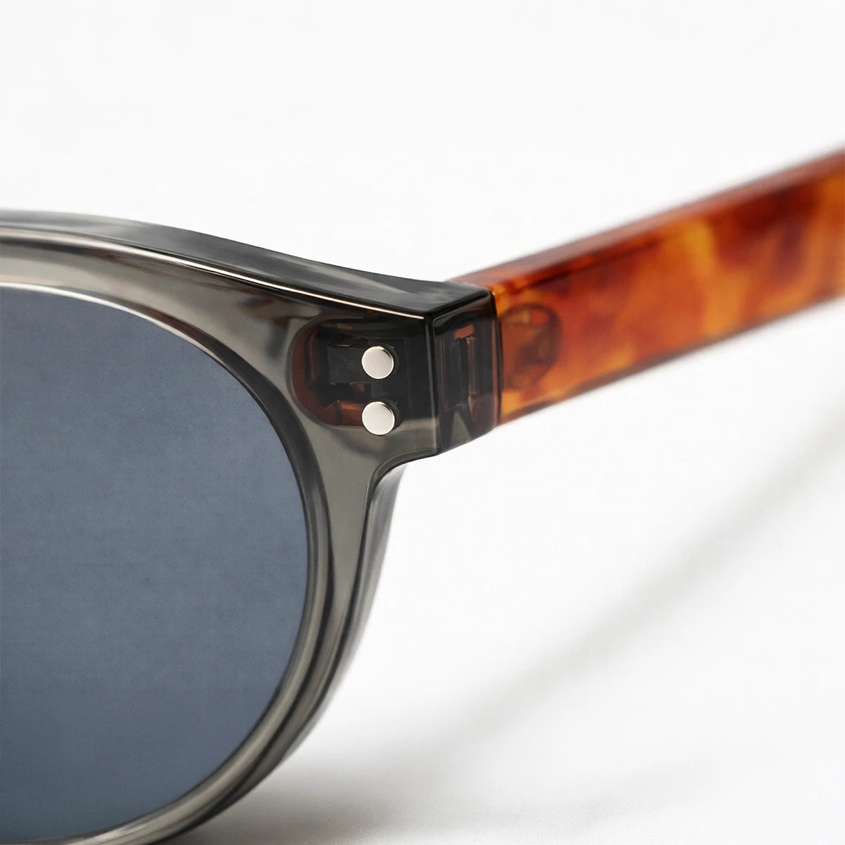 Gafas de sol redondeadas Paris Noir con montura negro translúcido, patillas de carey ámbar y lentes gris oscuro.
