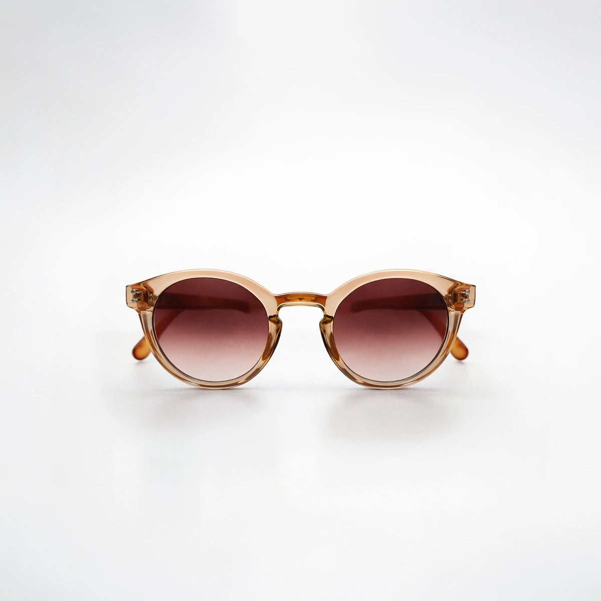 Gafas de sol redondeadas Paris Sunset con montura champagne translúcida, patillas de carey ámbar y lentes marrón rosado.

