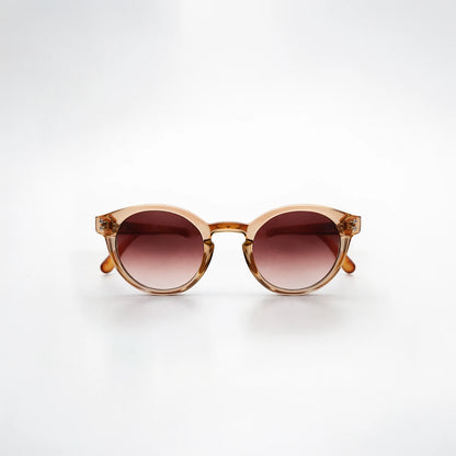 Gafas de sol redondeadas Paris Sunset con montura champagne translúcida, patillas de carey ámbar y lentes marrón rosado.
