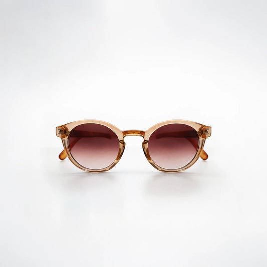 Gafas de sol redondeadas Paris Sunset con montura champagne translúcida, patillas de carey ámbar y lentes marrón rosado.
