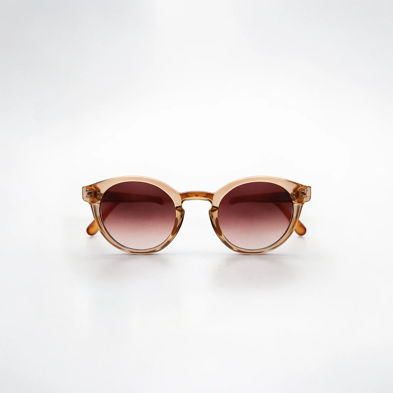 Gafas de sol redondeadas Paris Sunset con montura champagne translúcida, patillas de carey ámbar y lentes marrón rosado.
