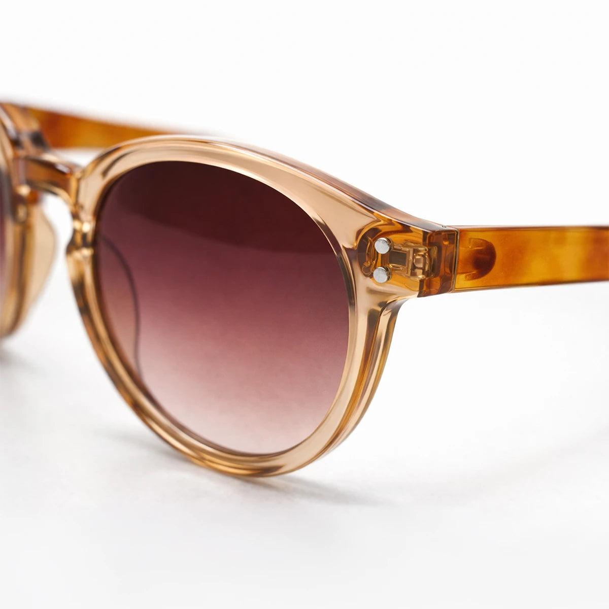 Gafas de sol redondeadas Paris Sunset con montura champagne translúcida, patillas de carey ámbar y lentes marrón rosado.
