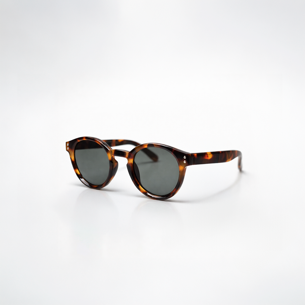 Gafas de sol redondeadas Paris Tortoise con montura en carey oscuro de diseño atemporal y lentes de sol gris oscuro.
