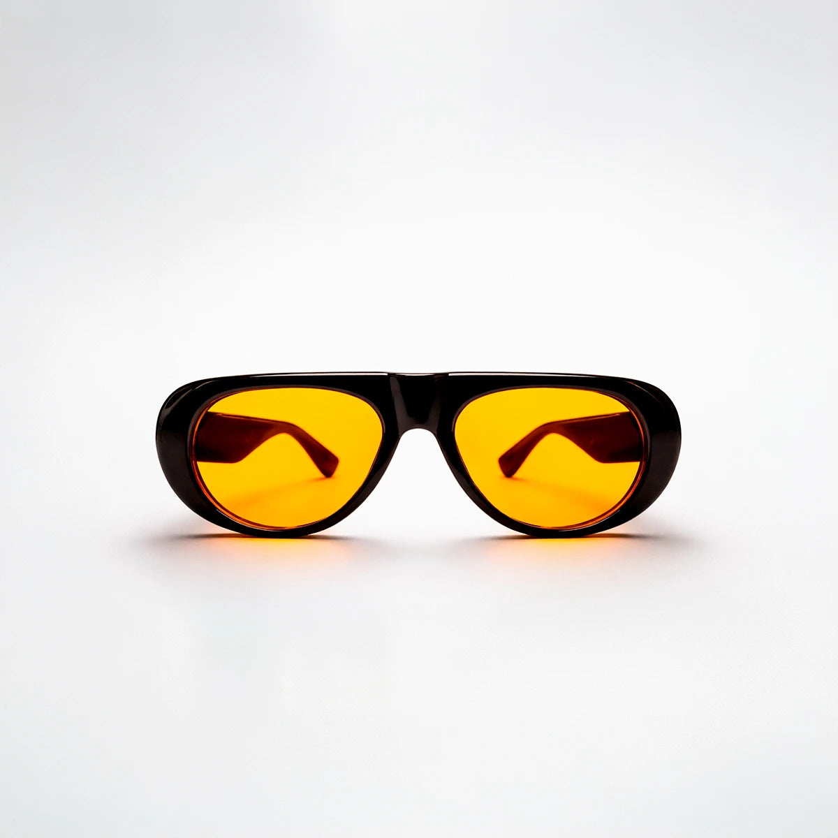 Gafas de sol ovaladas de montura gruesa negra Venice Sunset con lentes en tono amarillo naranja brillante.
